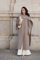a lady in a grey long wool coat and a pair of white wide leg pants
